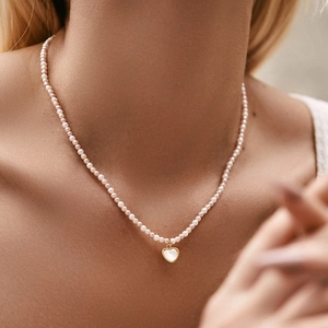 Handgemaakte parelketting met hartvormige parelmoeren hanger om de nek van een vrouw