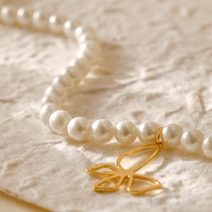 Elegante 18K vergulde parelketting met bloemenhanger op een gestructureerde achtergrond