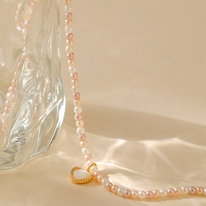 Roze en witte parelketting met gouden hartvormige hanger op zachte achtergrond