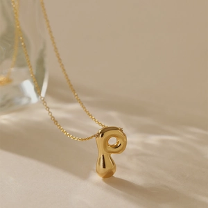 Macro detail of gold plated letter P pendant with glossy finish and fine O-chain