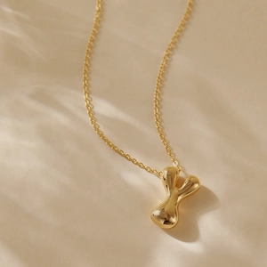 Detailed close-up of golden fluid irregular letter Y pendant with mirror polish finish