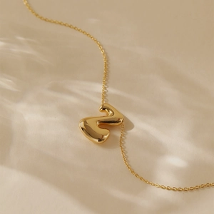 Detailed macro view of the gold plated lava-textured letter necklace with soft lighting