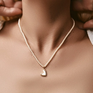 Klassieke parelketting met een onregelmatige vergulde hartvormige hanger op model