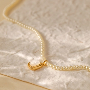 Klassieke vergulde parelketting met hartvormige schelphanger op getextureerd papier