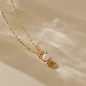 Elegante collana dorata con ciondolo gatto corona in perla su sfondo effetto acqua