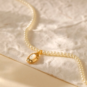 Franse retro parelketting met een goudkleurige getextureerde hanger en ingelegde schelp