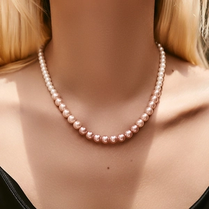 Detail van de parelketting met kleurverloop van wit naar zachte roségouden tinten op de huid