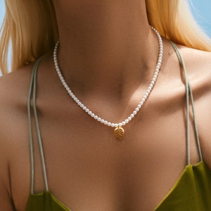 Elegante parelketting voor dames met gouden blad hanger op een fluwelen top model