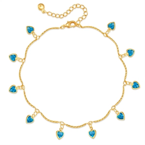 Détail d'une chaîne de cheville dorée ornée de onze breloques en zircon bleu en forme de cœur