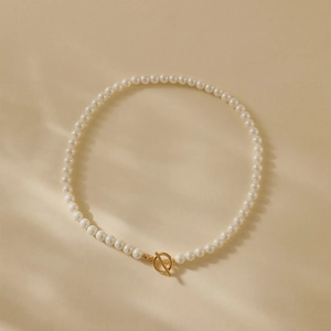 Elegante zoetwaterparelketting met 18K vergulde OT-sluiting op een warme stoffen achtergrond