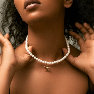 Close-up van handgemaakte parelketting met een gouden zeester hanger rond de hals