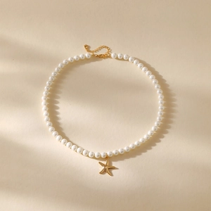 Detail van parelketting met gouden zeester hanger en verstelbare sluiting voor dames