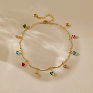 Détail de bracelet de cheville doré avec pendentifs en zircon colorés en cœur