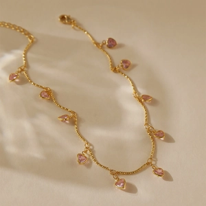 Détail de la chaîne dorée avec pendentifs zircons roses en forme de cœur