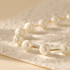 Detail van elegante witte parels aan een gouden ketting met spiraalvormige textuur