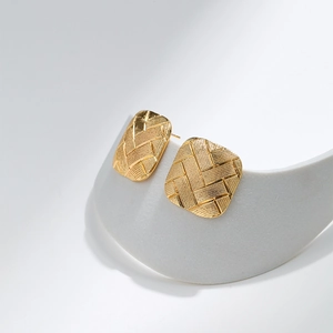 Close-up of golden geometric rectangular stud earrings with fine woven mesh texture