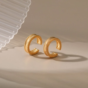 Gros plan détaillé de boucles d'oreilles dorées en C avec texture à rayures verticales