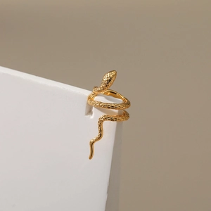 Gros plan d'un ear cuff serpent doré avec des textures d'écailles et un éclat métallique poli