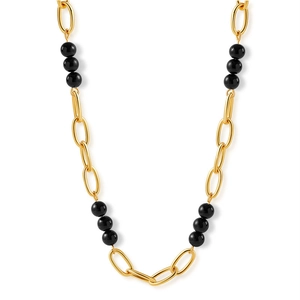 Collier multicouches plaqué or 18K avec perles noires sur fond blanc minimaliste