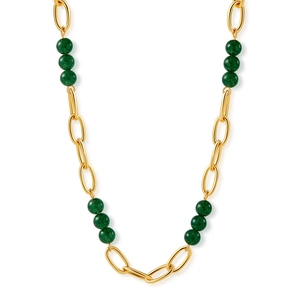Détail des maillons de chaîne dorés et perles de pierre verte sur un collier ras du cou
