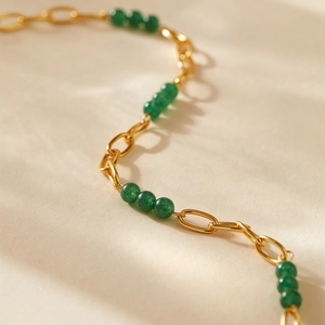 Vue détaillée macro du collier chaîne dorée bohème avec perles vert émeraude
