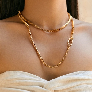 Double-layered gold box chain necklace with minimalist clasp worn on a model