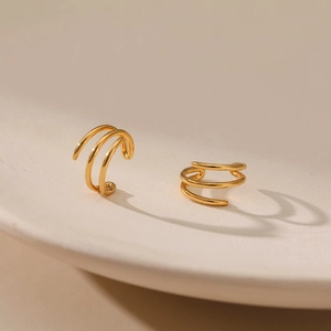 Vue détaillée du ear cuff triple épaisseur doré sur un plateau en céramique au fini lisse