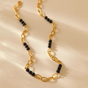 Détail du collier à couches plaqué or 18 carats avec perles noires polies et courbes en S