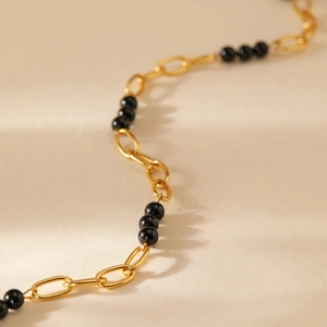 Détail de la chaîne plaquée or 18K avec perles noires et maillons ovales polis