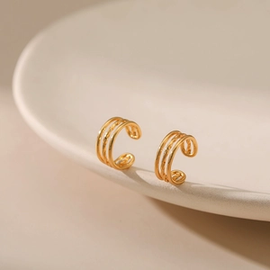 Détail d'un ear cuff doré multicouche avec texture corde torsadée sur plateau céramique