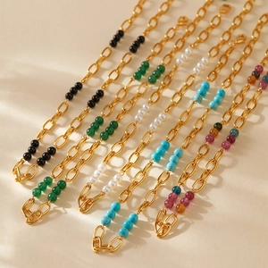 Collier bohème en chaîne dorée avec perles de turquoise et nacre sur fond beige