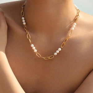 Collier bohème à chaîne trombone dorée et perles blanches sur le cou d'une femme