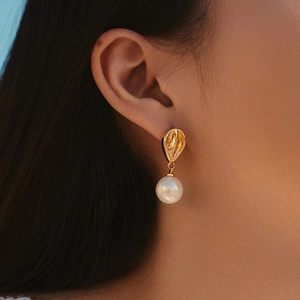 Elegante Vintage-Ohrringe mit Goldherz und Perlenanhänger an einem weiblichen Model