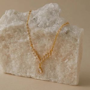 Dettaglio collana placcata oro 18K con diamanti a V e ciondolo a goccia trasparente