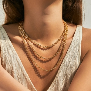 Three-layer layered gold circle link chain necklace worn by a model in natural light