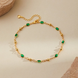 Detailed view of adjustable gold anklet with green teardrop stones and faceted beads