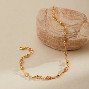 Detail of 18K gold-plated anklet with orange teardrop crystals on natural stone