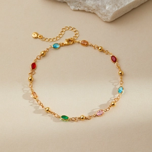 Detail of colorful oval gemstones on an 18K gold-plated adjustable ankle chain