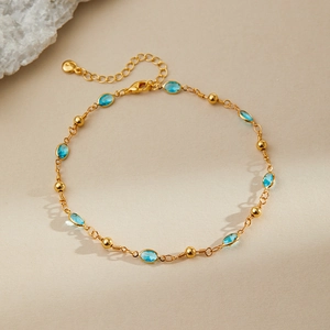 Detail of gold-plated anklet featuring sky blue oval stones and round beads close-up