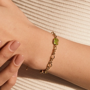 Elegante bracciale a catena dorata con pendente in pietra verde quadrata al polso