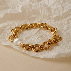 Dettaglio ravvicinato di un bracciale a catena dorata con una perla barocca bianca unica