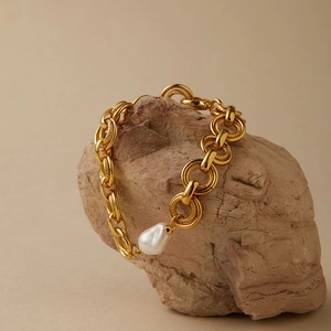 Bracciale a catena spessa placcato oro 18K con perla barocca su sfondo di roccia naturale