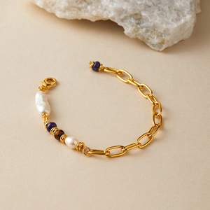 Dettaglio di bracciale con catena dorata, perle barocche e perline viola eleganti