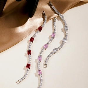 Detailed close-up of sparkling tennis bracelets with red, pink and white stones on silk