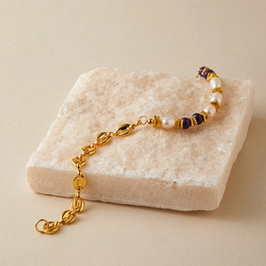 Dettaglio del bracciale di perle con catena chicco di caffè dorata e pietre viola