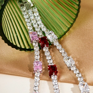 Detail of tennis bracelets with pink, red, and white square stones on satin
