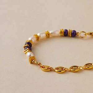 Dettaglio macro di bracciale elegante con catena dorata e perle barocche raffinate