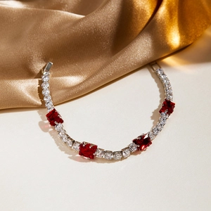 Detail of luxury tennis bracelet with silver base, red ruby-style gems and white zircons