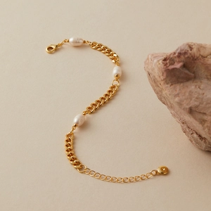 Dettaglio del bracciale a catena dorata con tre perle e chiusura regolabile in stile boho