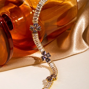 Macro shot of gold plated bracelet with square zircons and purple heart clover charms